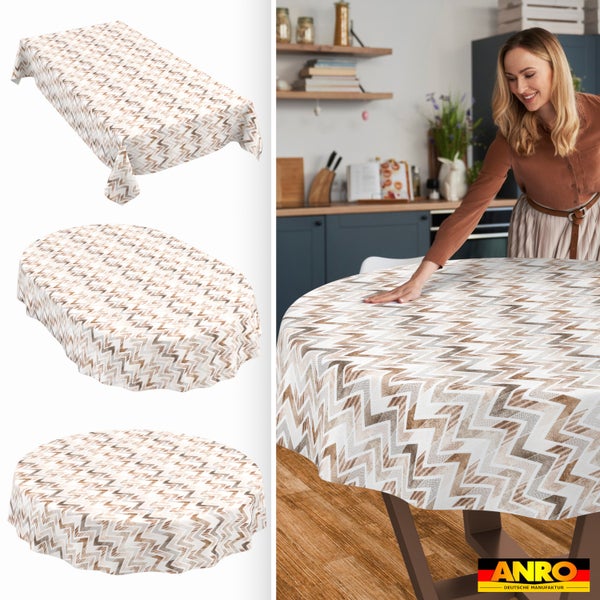 Wachstuch-Tischdecke mit Zickzack-Muster, eckig, oval und rund. Frau legt die Tischdecke auf einen Küchentisch. ANRO DEUTSCHE MANUFAKTUR Logo.