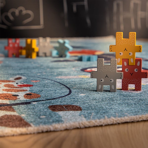 Holzstapelfiguren in Tierform auf einem gemusterten Kinderteppich als Spielzeug für Kinderzimmer.