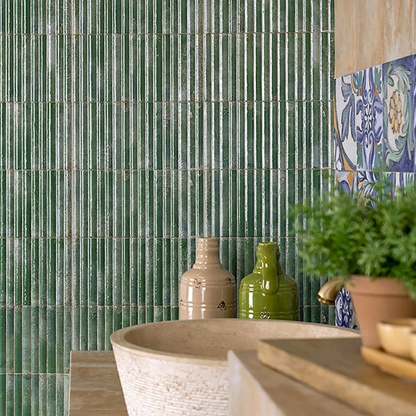 Wand mit gerippten Fliesen in einer Badezimmerumgebung mit Natursteinwaschbecken und dekorativen Elementen.