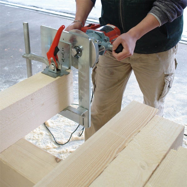 Handwerker verwendet eine elektrische Schlitzfräse zur Holzbearbeitung an einem massiven Holzbalken in einer Werkstatt.