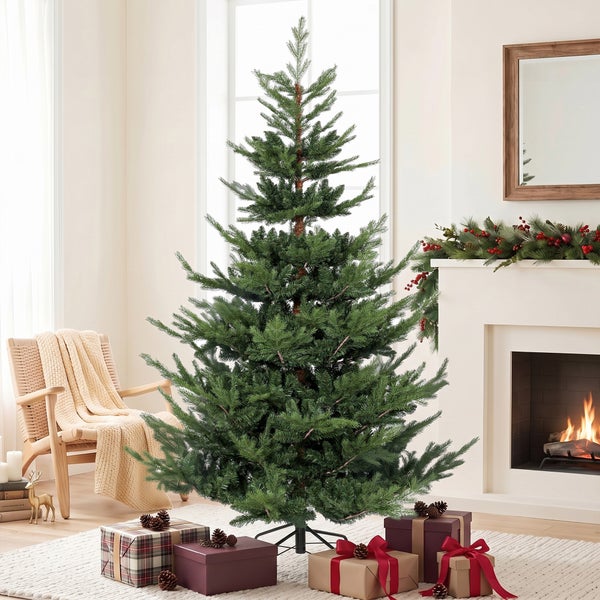 Künstlicher Weihnachtsbaum in einem gemütlichen Wohnzimmer vor einem Kamin mit Weihnachtsgeschenken.