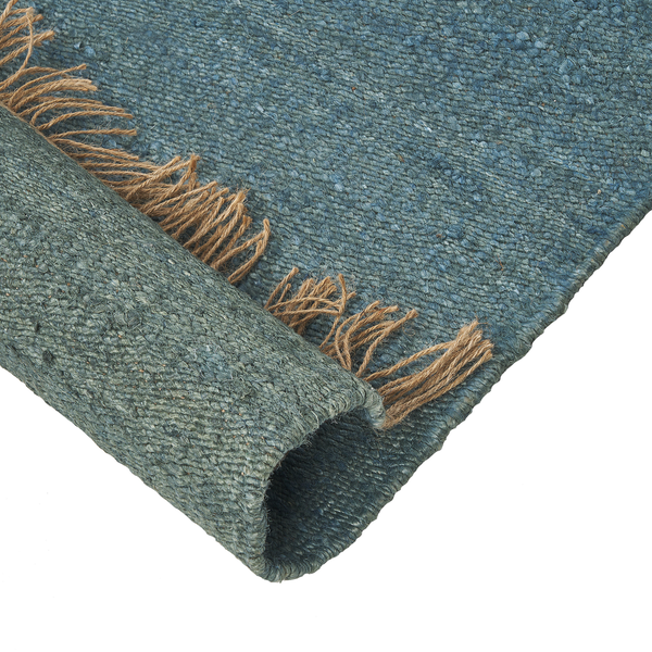 Gewebter blauer Teppich mit braunen Fransen, Detailansicht der Textur und einer umgeschlagenen Ecke.