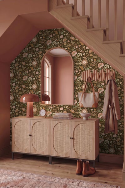 Tapete mit floralem Muster, Wandspiegel mit Goldrahmen, Marmortisch mit Holzbeinen, dekorative Vasen und Kerzenständer.