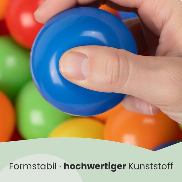 Hand drückt einen formstabilen Bällebadball aus hochwertigem Kunststoff zusammen.
