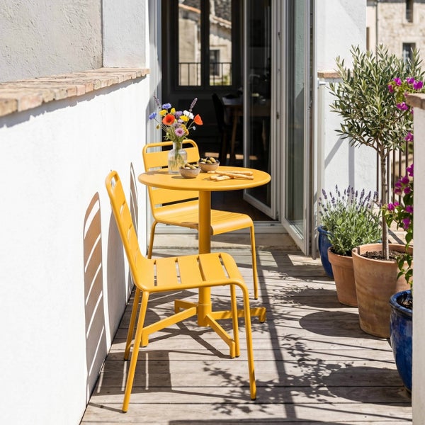 Runder Bistrotisch aus gelbem Metall mit vierbeinigem Gestell.