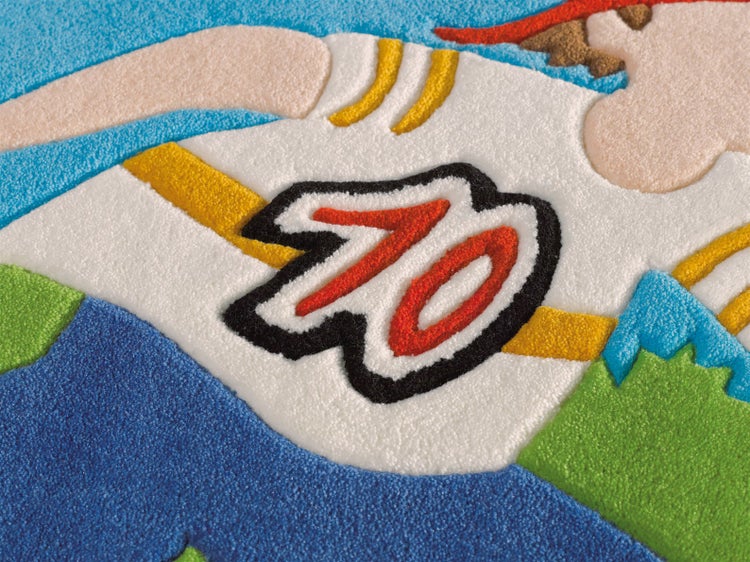 Detailaufnahme eines weichen Kinderteppichs mit Comic-Motiv und einer Zahl.