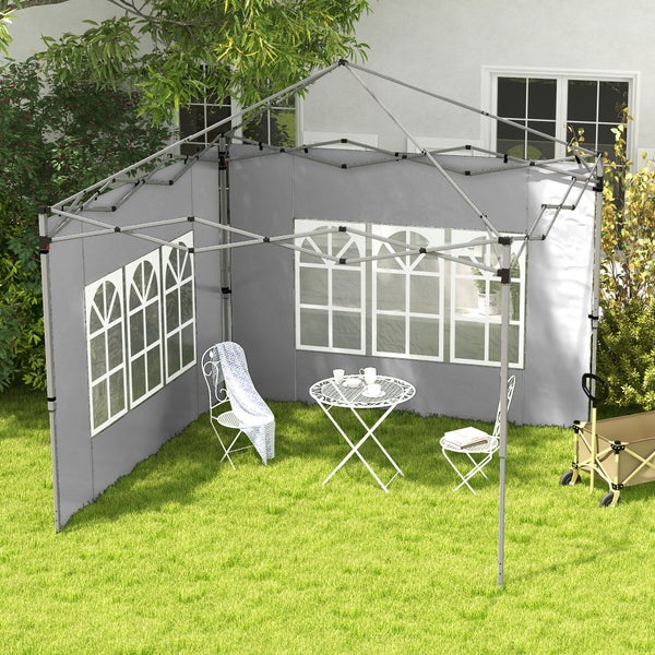 Grauer Faltpavillon mit zwei Seitenwänden und Fenstern auf einer Rasenfläche mit weißen Gartenmöbeln und einem Bollerwagen.