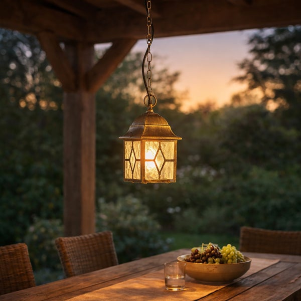 Rustikale Außenpendelleuchte im Laternen-Design mit Kette über einem gedeckten Holztisch auf einer Terrasse in der Dämmerung.
