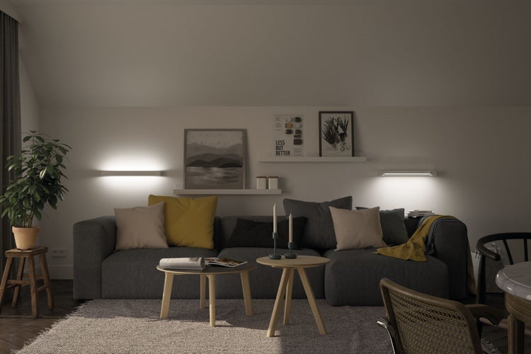 Modernes Wohnzimmer mit grauem Sofa, runden Holztischen und indirekter Beleuchtung durch flache LED-Wandleuchten an der Wand über der Couch.