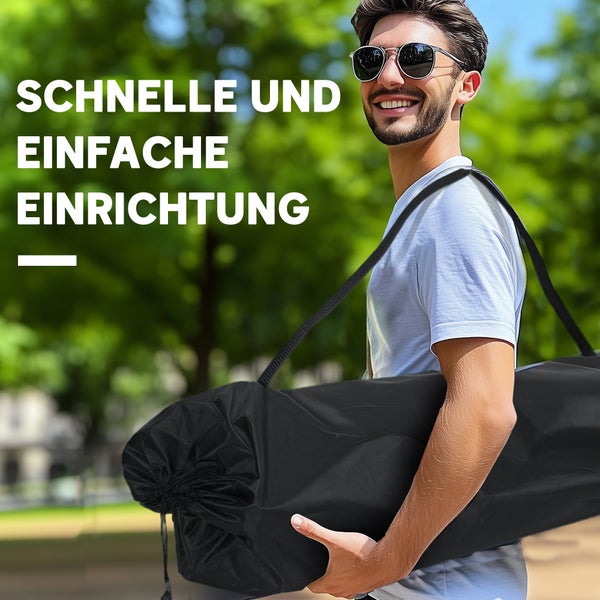 Ein Mann trägt eine schwarze Tasche mit Ausrüstung für eine einfache Einrichtung im Freien.