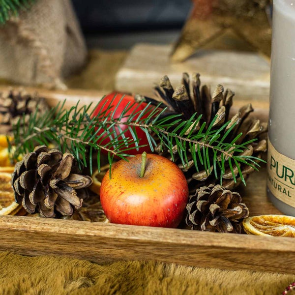 Dekorationstablett mit Äpfeln, Tannenzweigen, Tannenzapfen und Kerze