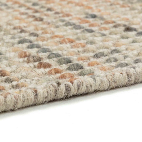 Nahaufnahme eines strukturierten, mehrfarbigen Wollteppichs mit Noppenoberfläche und gewebter Kante.