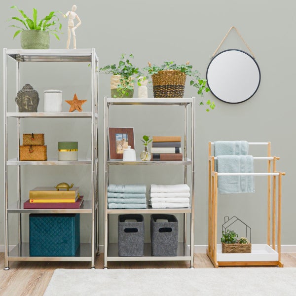 Modernes helles Zimmer mit verchromten Metallregalen, Bambus-Handtuchhalter, rundem Spiegel und verschiedenen Dekorationsartikeln.