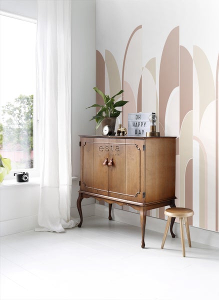 Holzschrank mit Dekoration und Hocker vor einer Wand mit Muster