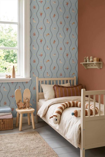 Kinderzimmer mit hellblauer Zirkus-Motivtapete, Holzgestellbett, Hasenstuhl und terracottafarbener Wand.