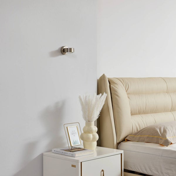 Szene eines Schlafzimmers mit einem Bett, einem Nachttisch und einer Wandleuchte.