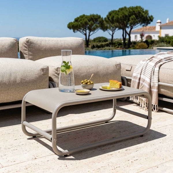 Moderner Gartenbeistelltisch aus beigem Metall auf einer hellen Terrasse am Pool mit Lounge-Möbeln.