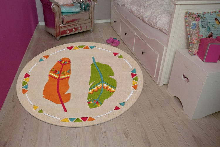 Runder Kinderteppich mit Feder Motiven in einem spielerisch eingerichteten Kinderzimmer mit Bett und Sessel auf hellem Holzboden.