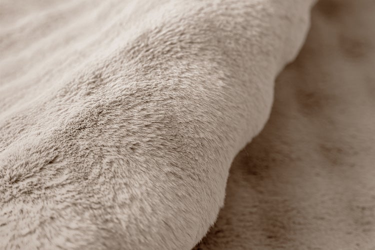 Nahaufnahme eines weichen Kunstfellteppichs mit plüschiger Textur.
