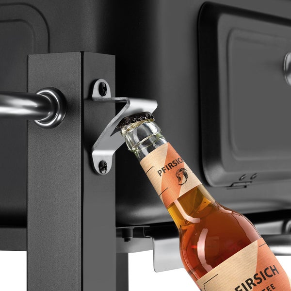 Integrierter Flaschenöffner aus Metall an einem schwarzen Grill mit einer Glasflasche beim Öffnen.