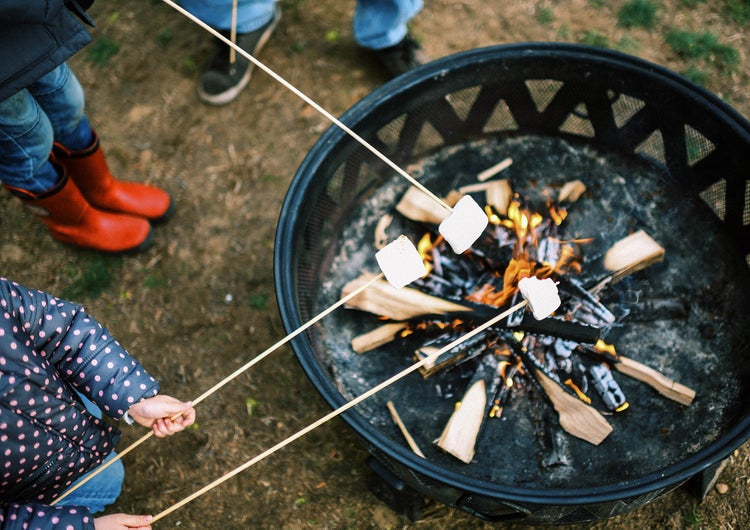 Marshmallows werden über einem Feuer in einer Feuerschale geröstet.