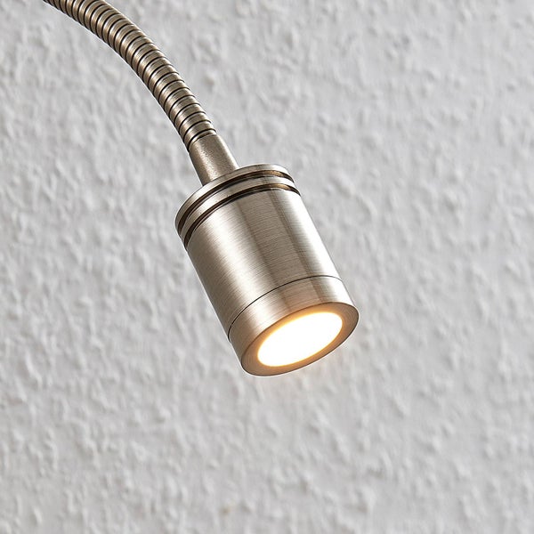 LED Wandleseleuchte mit flexiblem Schwanenhalsarm aus Metall, montiert neben einem Holzbett über Büchern auf einem Nachttisch.