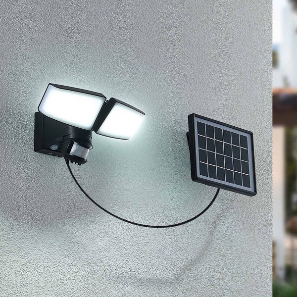 Solar-LED-Außenwandstrahler mit zwei schwenkbaren Köpfen, Bewegungssensor und separatem Solarpanel montiert an einer Wand.