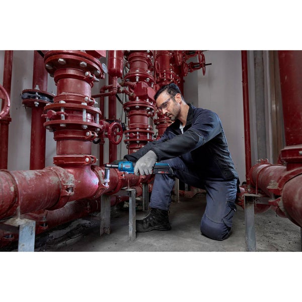 Ein Mann mit Schutzbrille bedient einen Akku-Drehschlagschrauber an einem Rohrsystem.