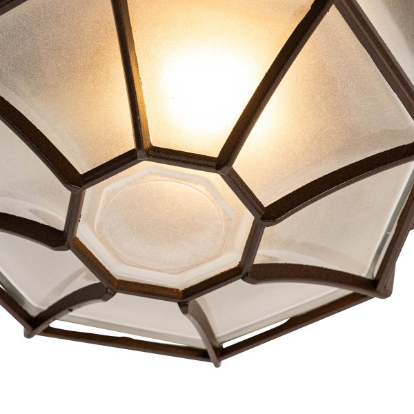Detailansicht einer Außenleuchte mit geometrischem Metallrahmen und matten Glasscheiben sowie warmem Lichtschein.