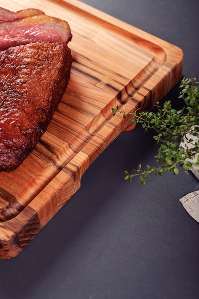 Servierbrett aus Holz mit gebratenem Fleisch und Thymian