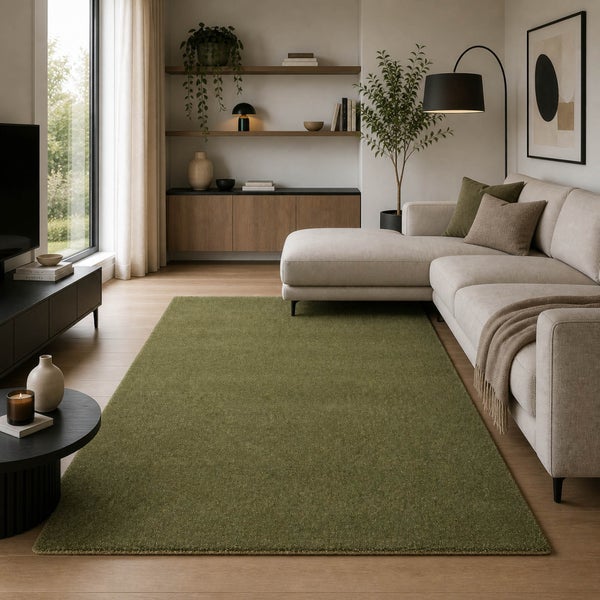 Modernes Wohnzimmer mit großem grünen Teppich, hellem Ecksofa, schwarzer Stehlampe und Holzmöbeln auf Parkettboden.