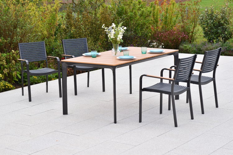 Gartenszene mit Esstisch und Stühlen auf einer Terrasse.