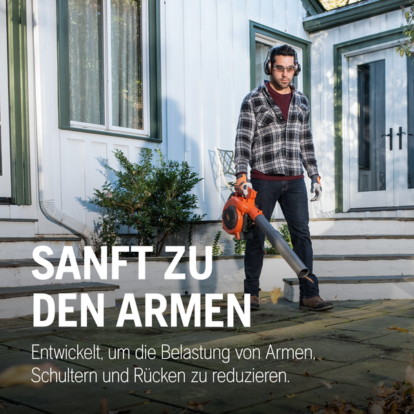 Mann mit Laubbläser vor einem Haus