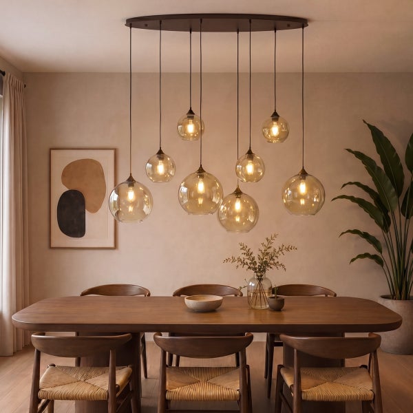 Modernes Esszimmer mit Holztisch, Stühlen und einer Pendelleuchte mit neun Glaskugeln. Warme Beleuchtung und abstrakte Wandkunst.
