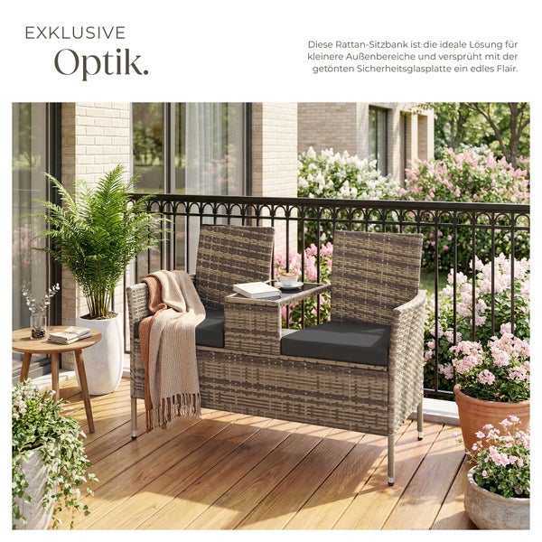Polyrattan-Balkonbank für zwei Personen mit integriertem Glastisch in der Mitte, grauen Sitzkissen und Decke auf einer Holzterrasse mit Pflanzen.