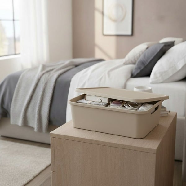 Aufnahme eines Schlafzimmers mit einem beigen Aufbewahrungsbehälter mit Deckel auf einem Nachttisch