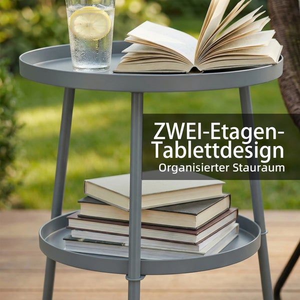 Runder Beistelltisch aus Metall mit zwei Etagen im Garten, oben ein Buch und Glas, unten ein Stapel Bücher.