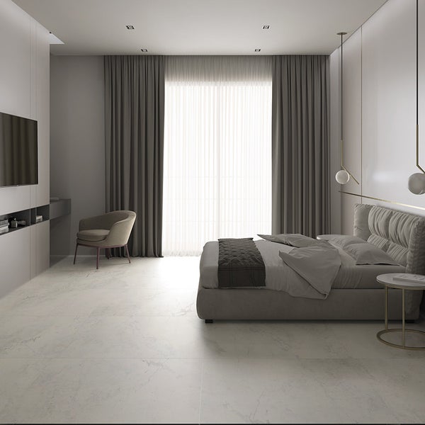Modernes Schlafzimmer mit großformatigen Fliesen in Marmoroptik, einem Doppelbett, einem Sessel und bodentiefen Vorhängen für ein elegantes Design.