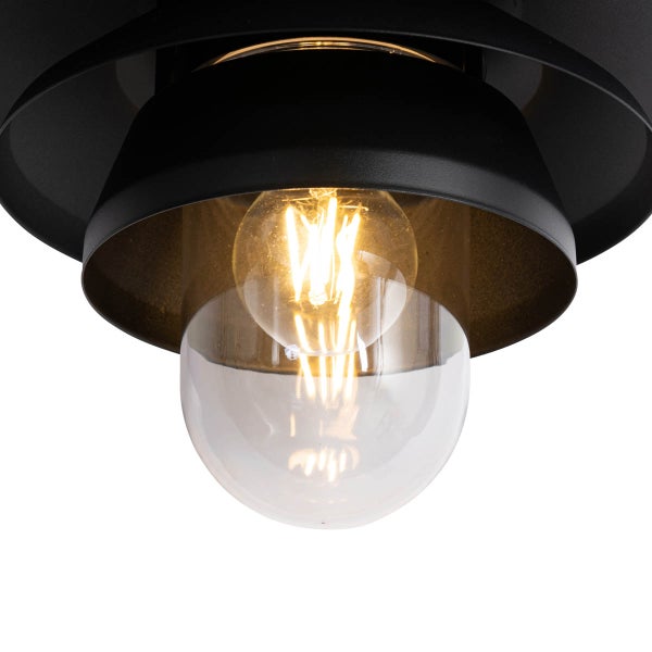 Detailansicht einer schwarzen Leuchte mit klarem Glaseinsatz und brennendem LED-Filament-Leuchtmittel.