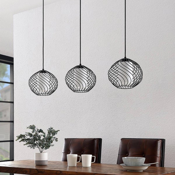 Drei schwarze Pendelleuchten mit dekorativem Drahtschirm über einem Esstisch.