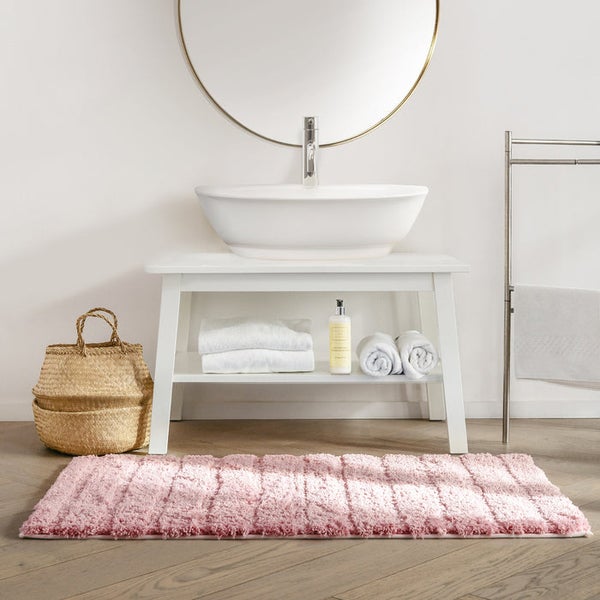 Badezimmer-Szene mit Waschbecken, Spiegel, Handtüchern, Aufbewahrungskorb und Badteppich