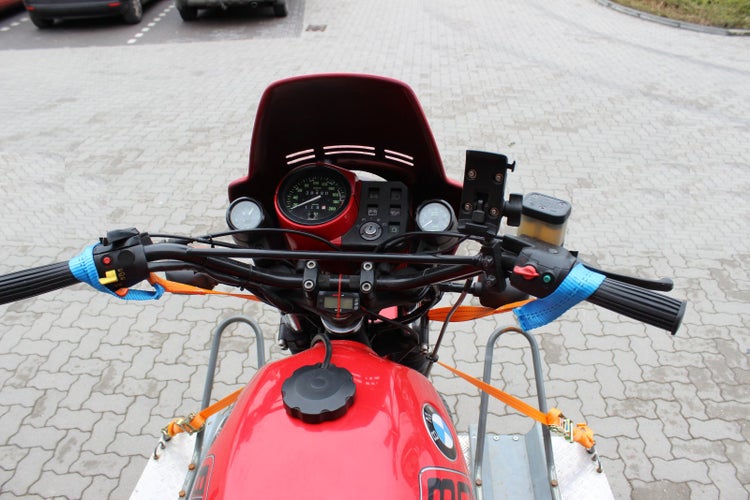 Blick auf das Cockpit eines Motorrads mit Kraftstofftank und Spanngurten zur Transportsicherung auf einer Ladefläche.