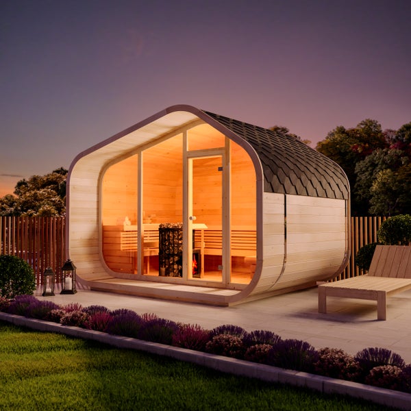 Moderne Außensauna aus Holz in Pod-Form mit Glasfront, Saunaofen und Sitzbänken auf einer beleuchteten Terrasse im Garten.