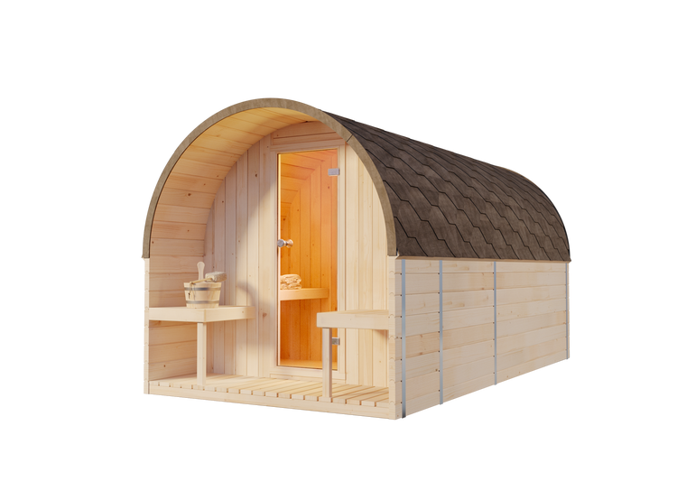 Fasssauna aus hellem Holz mit gewölbtem Dach und Schindeln auf einer Terrasse im Garten bei Sonnenuntergang.