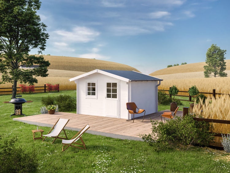 Weißes Gartenhaus aus Holz mit Satteldach auf einer Holzterrasse in einem hellen Garten mit Grill, Liegestühlen und einer hügeligen Landschaft.