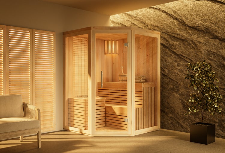 Ecksauna aus Holz mit Glaselementen in einem hellen Raum neben einer Steinwand und einem Sessel.