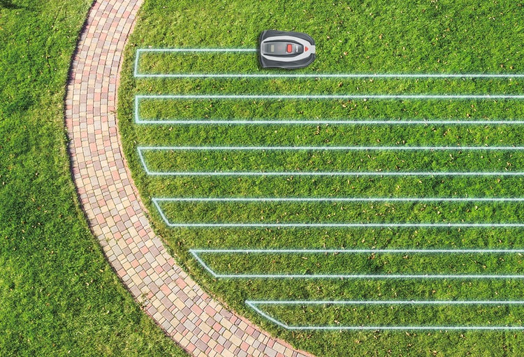 Mähroboter auf einer Rasenfläche neben einem gepflasterten Weg zeigt ein systematisches Mähmuster in geraden Bahnen.